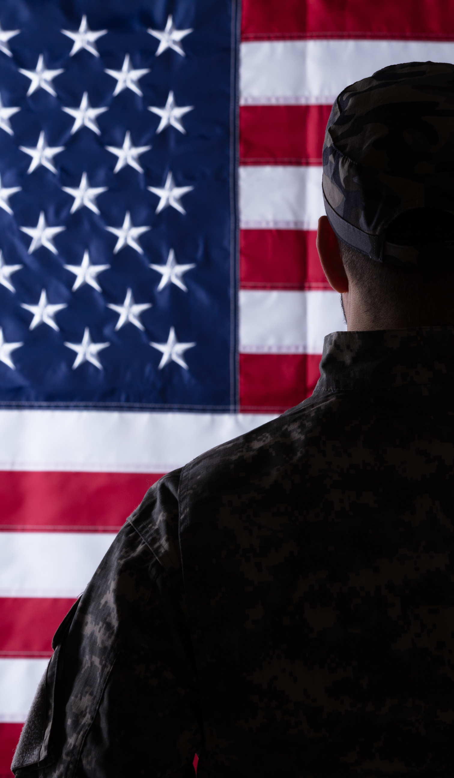 a soldier is standing in front of an american flag .
