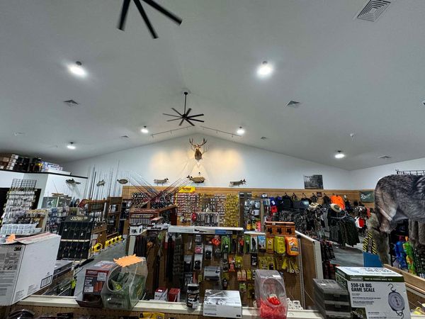 The inside of a hunting store with a ceiling fan hanging from the ceiling.