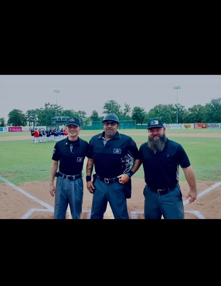Three men are standing next to each other on a baseball field.