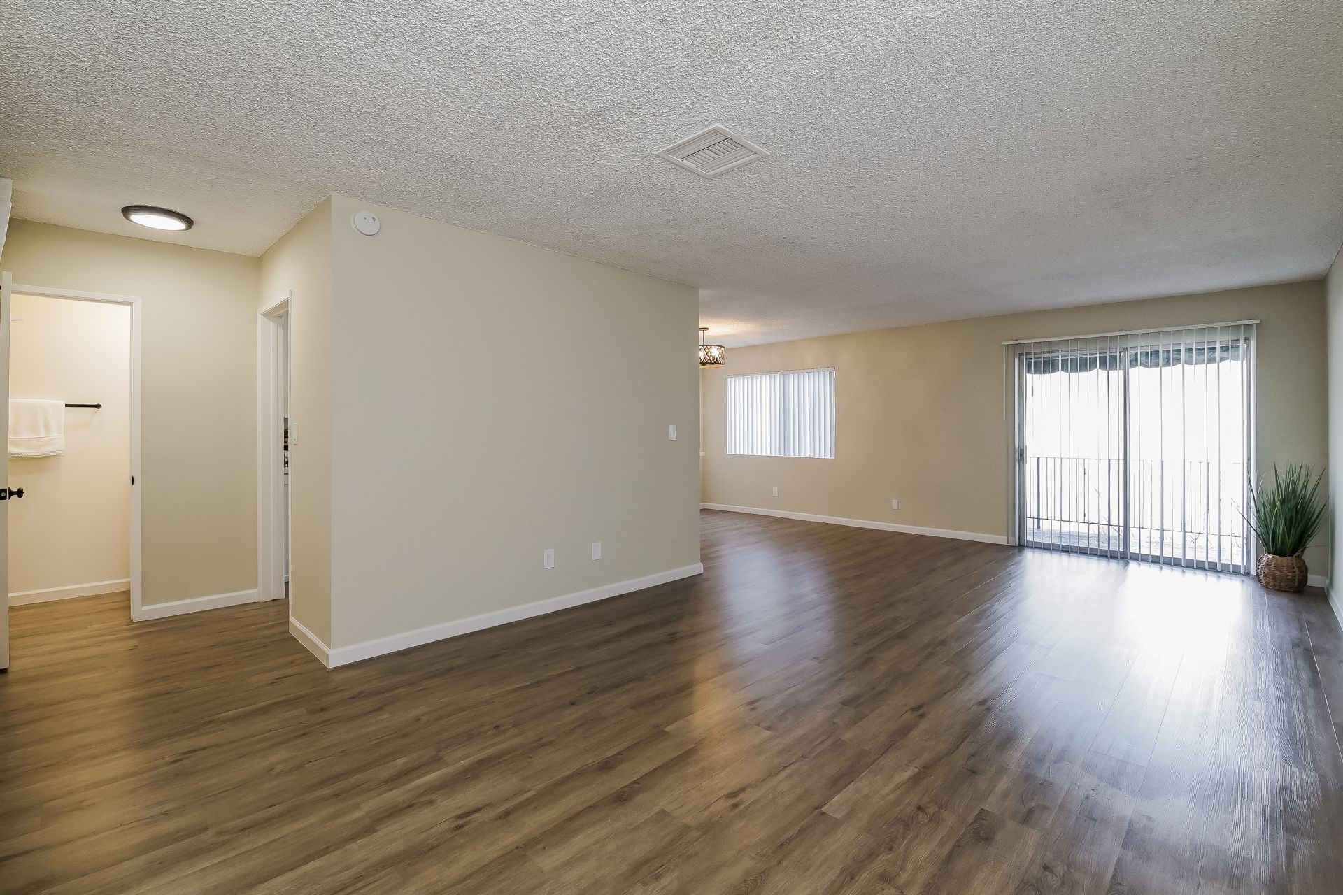 An empty living room with hardwood floors and sliding glass doors.