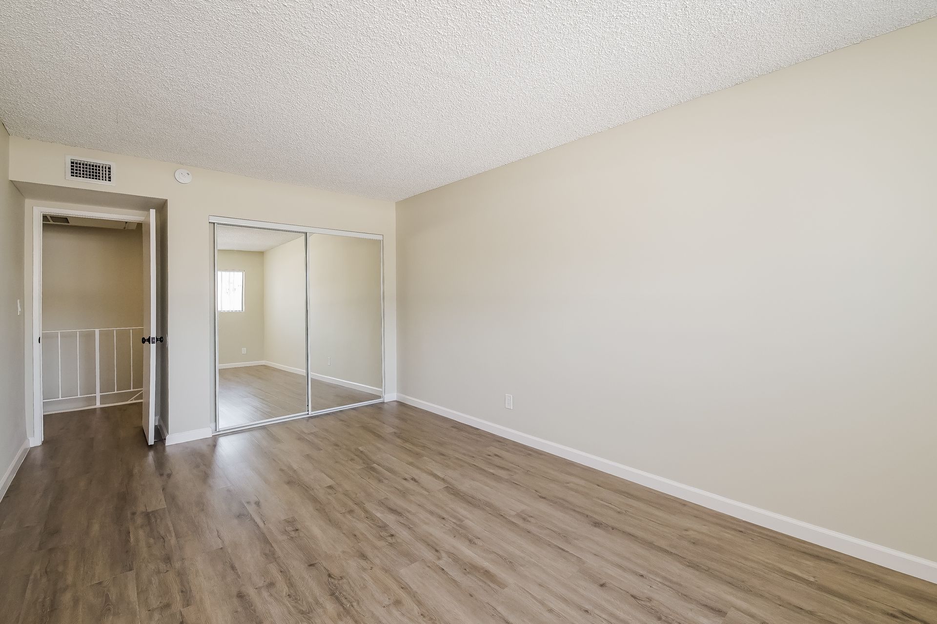 An empty living room with hardwood floors and a sliding glass door.