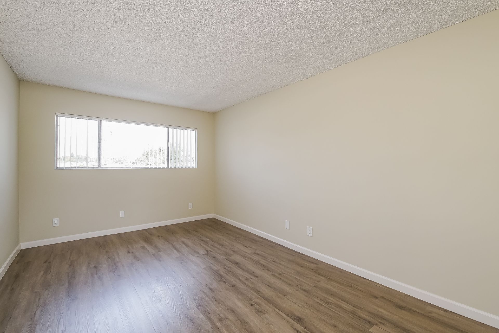 An empty living room with hardwood floors and a sliding glass door.