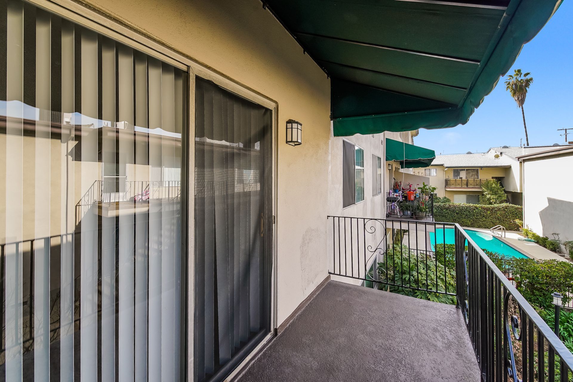 A balcony with a sliding glass door and a green awning over it.