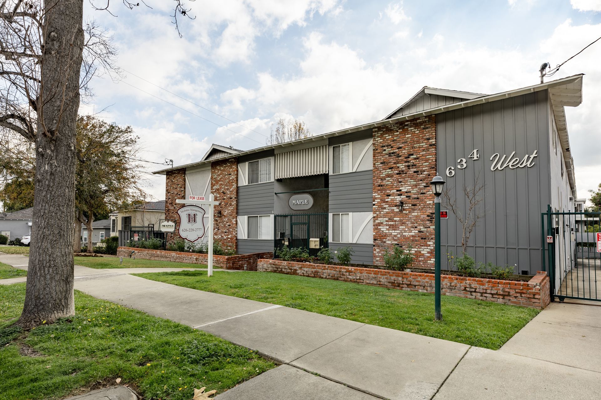 A large apartment building with a sidewalk and a tree in front of it.