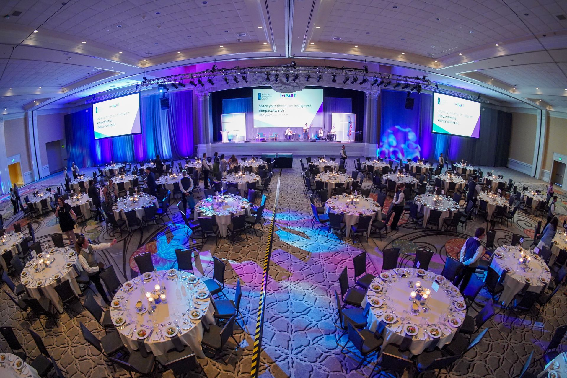 a large room filled with tables and chairs and a stage at the AHA awards.