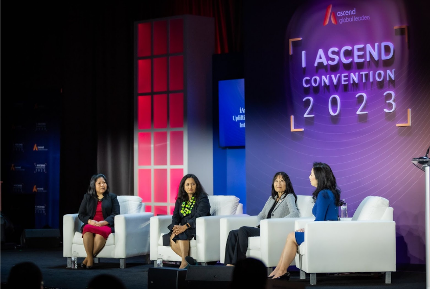 a group of women are sitting in chairs on a stage presentation at the Ascend Convention.