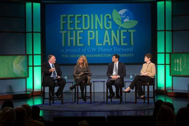 a group of people presenting at the Feeding the Planet conference in front of a sign that says feeding the planet