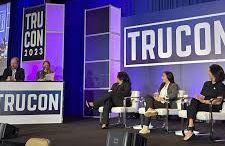 a group of people are sitting on a stage at the trucon conference answering questions.