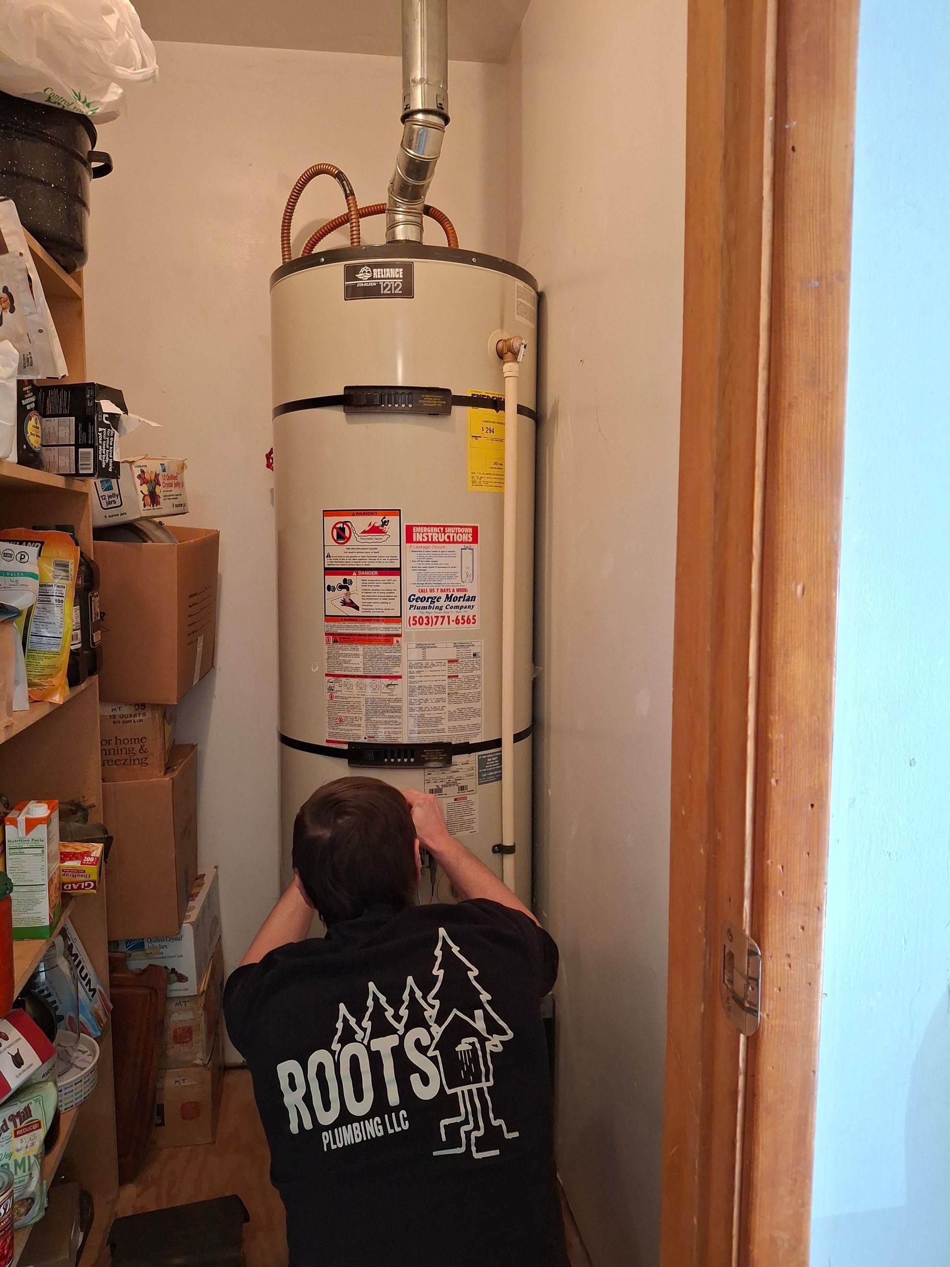 A man is working on a water heater in a room