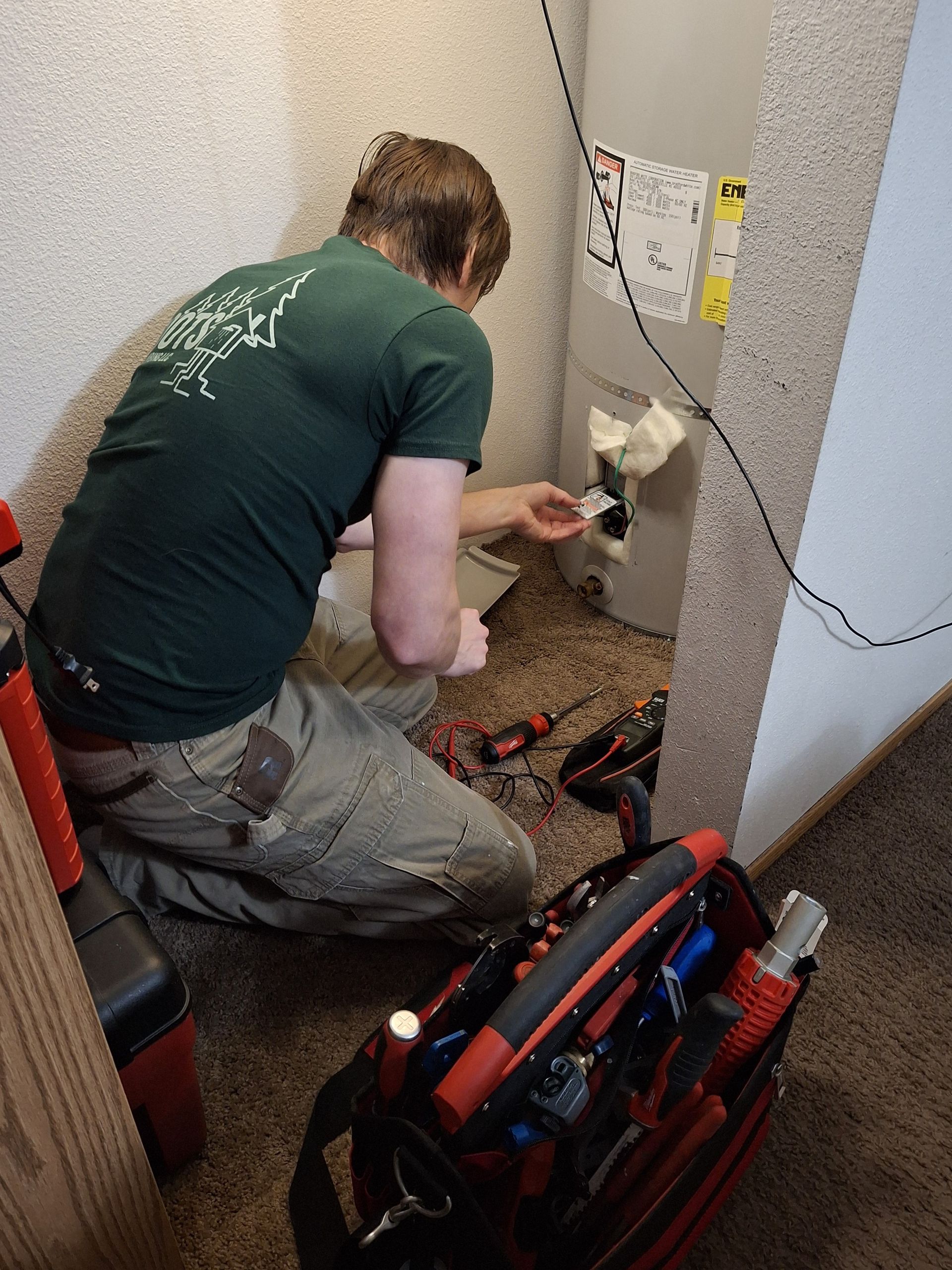 A man in a green shirt is working on a refrigerator