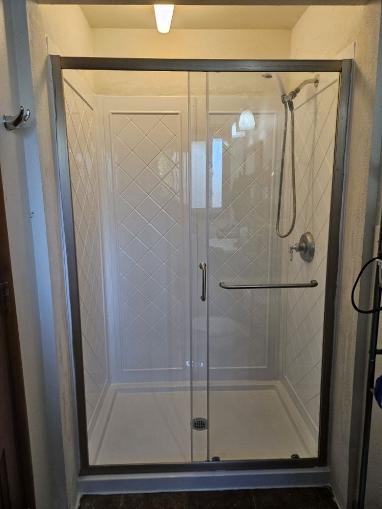 A bathroom with a sliding glass shower door and a shower head.