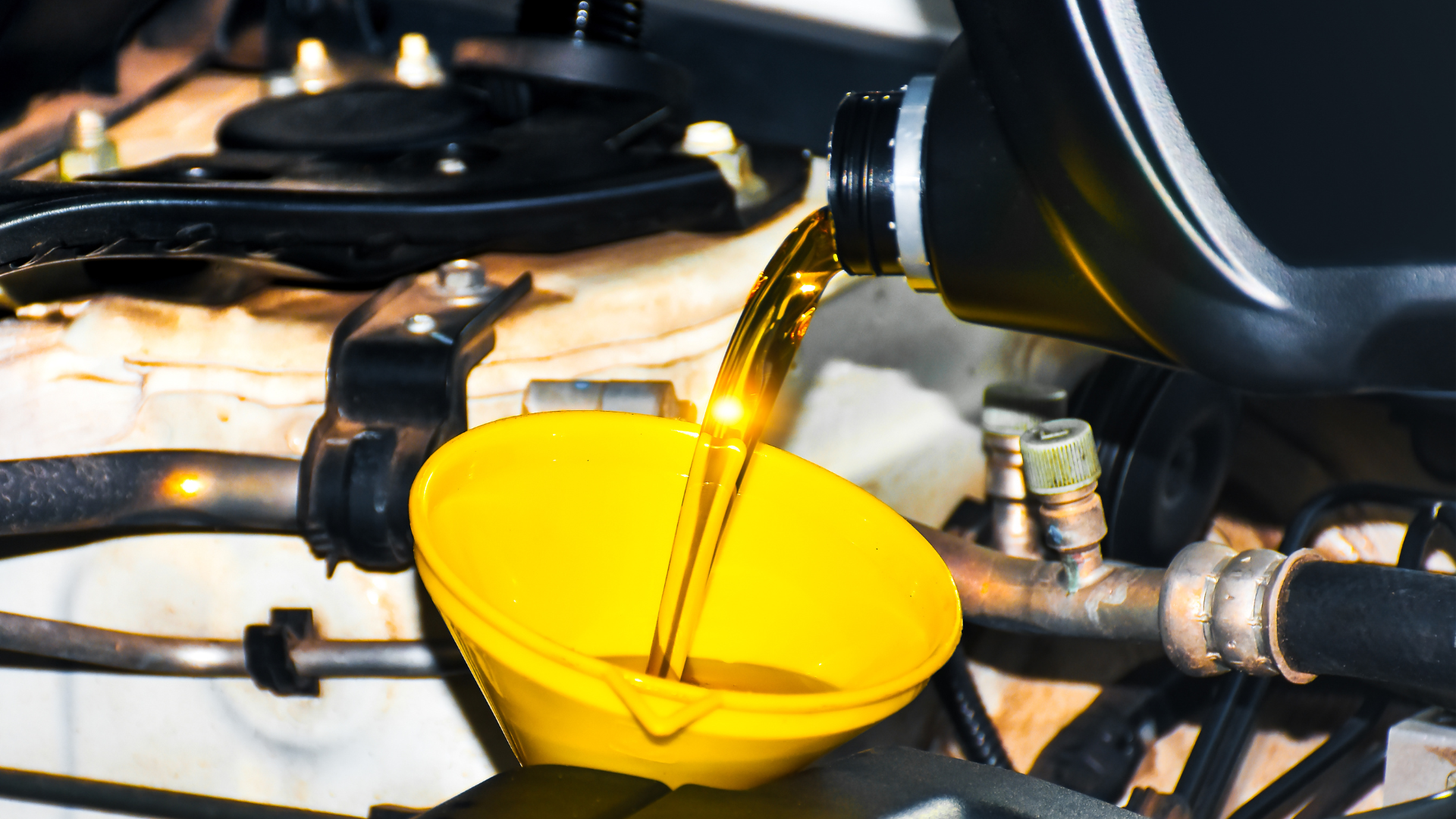 Pouring fresh oil into a car engine using a funnel; close-up view.