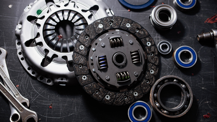 Clutch and other car parts, including bearings and wrenches, arranged on a dark surface.