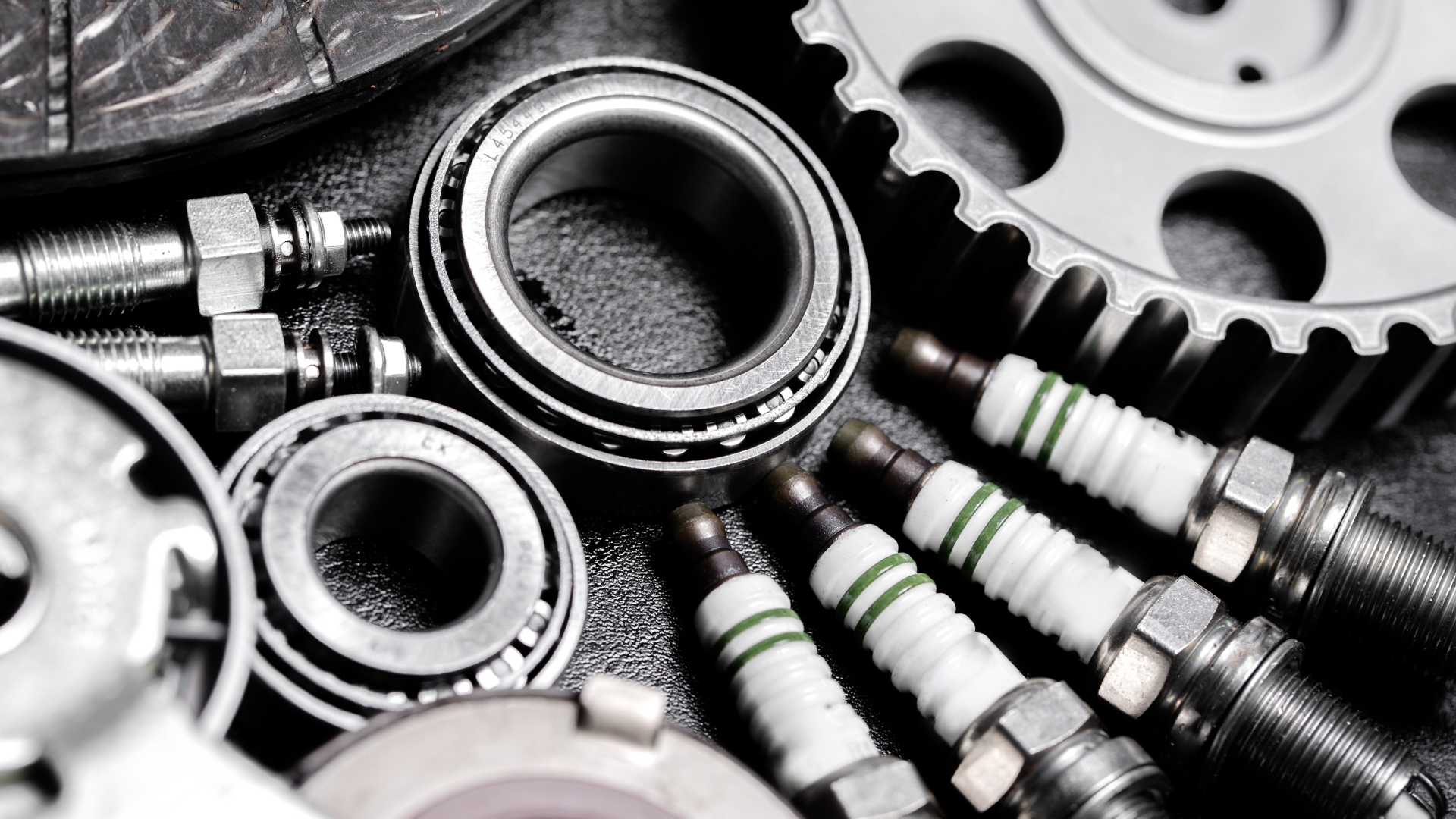 Assortment of automotive parts, including bearings, spark plugs, and gears.