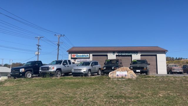 Vehicles parked in front of a garage with blue sky.