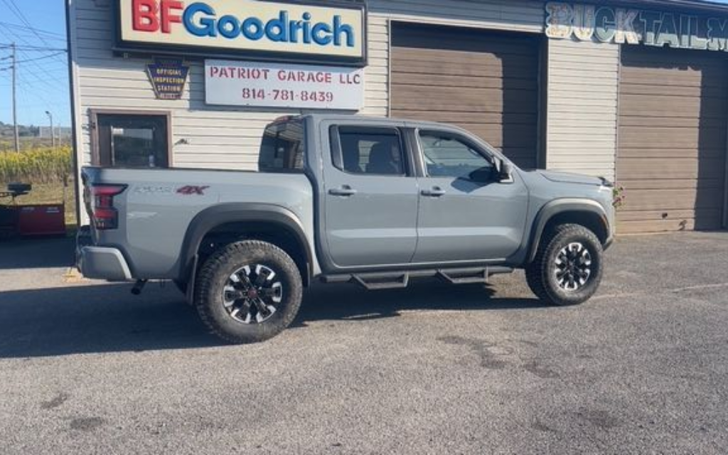 Gray pickup truck parked in front of a tire shop, with the 