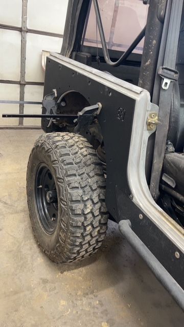Black Jeep's rear wheel and body panel. The black tire is mounted; the panel has a hinged opening.