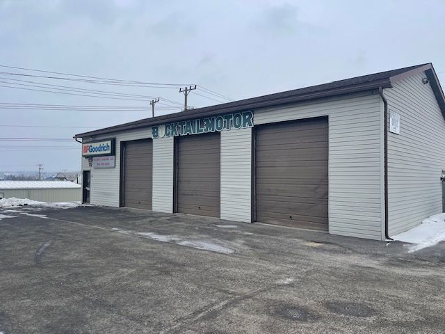 Exterior of a repair shop with three garage doors. Sign reads 