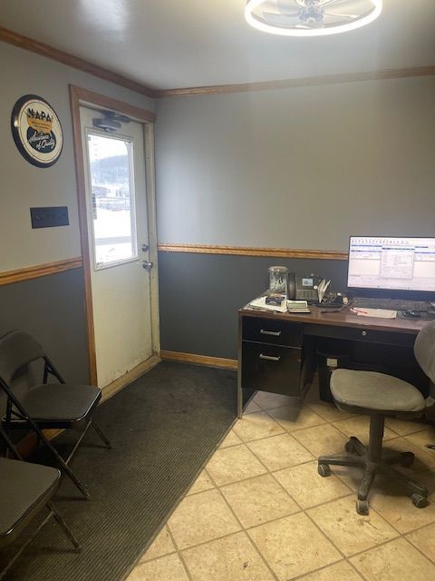 Auto shop waiting area: desk, computer, chairs, exit door, NAPA sign on wall.