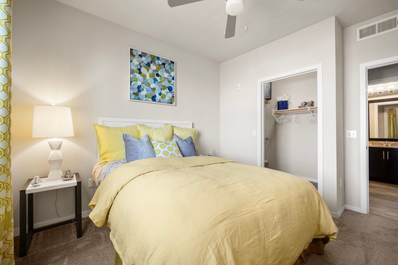 Bright bedroom with yellow bedding, decorative pillows, and an open closet door.