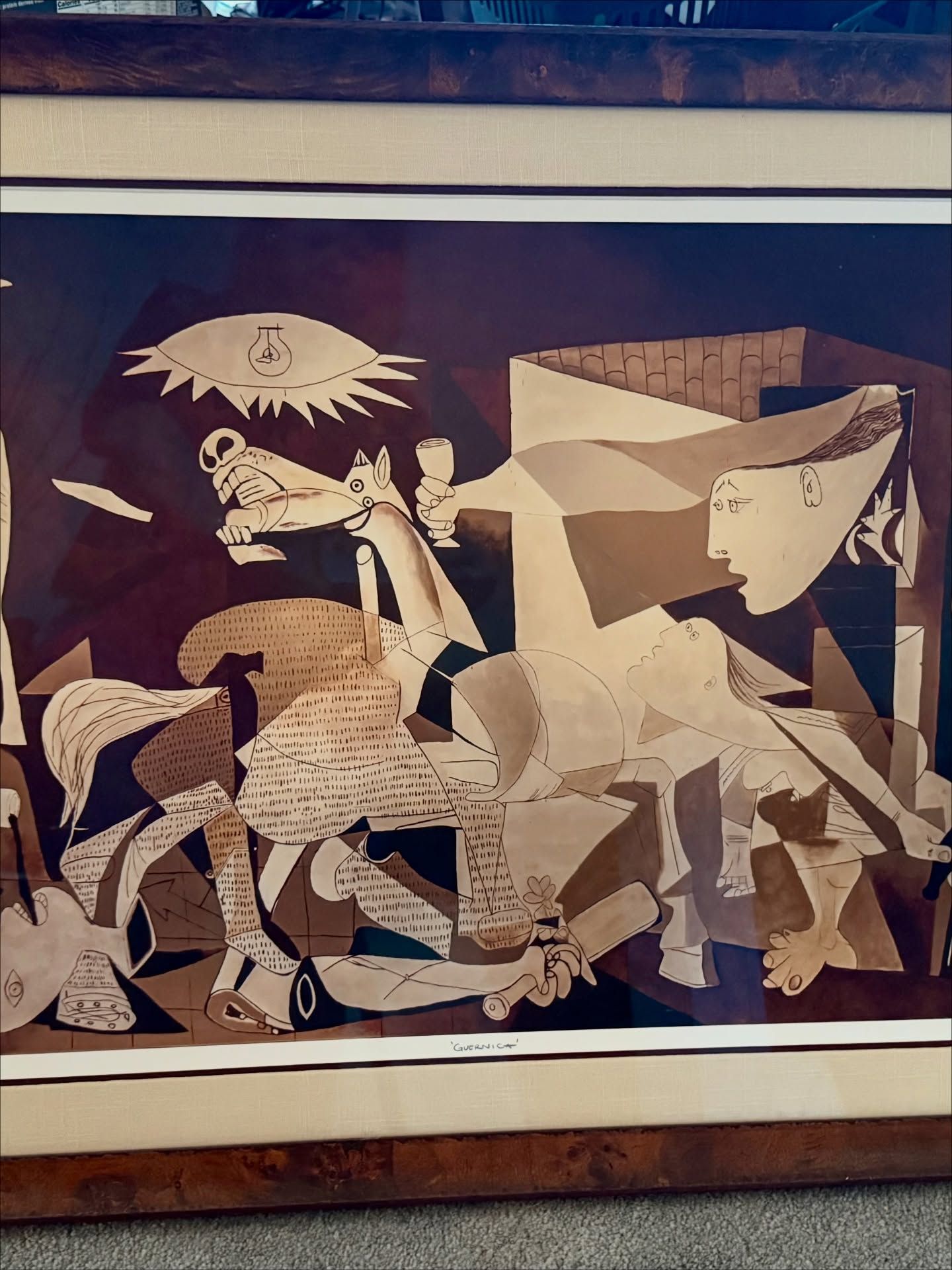 A print of Pablo Picasso’s Guernica, depicting abstracted, pained figures and a horse in grayscale tones.