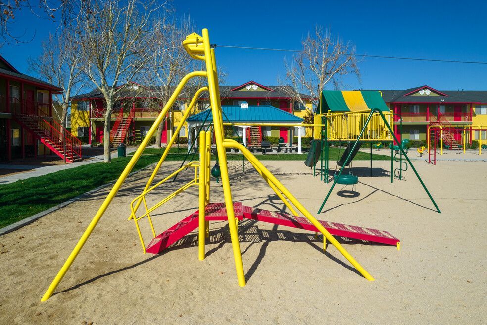 A playground with a yellow swing set in the middle of it