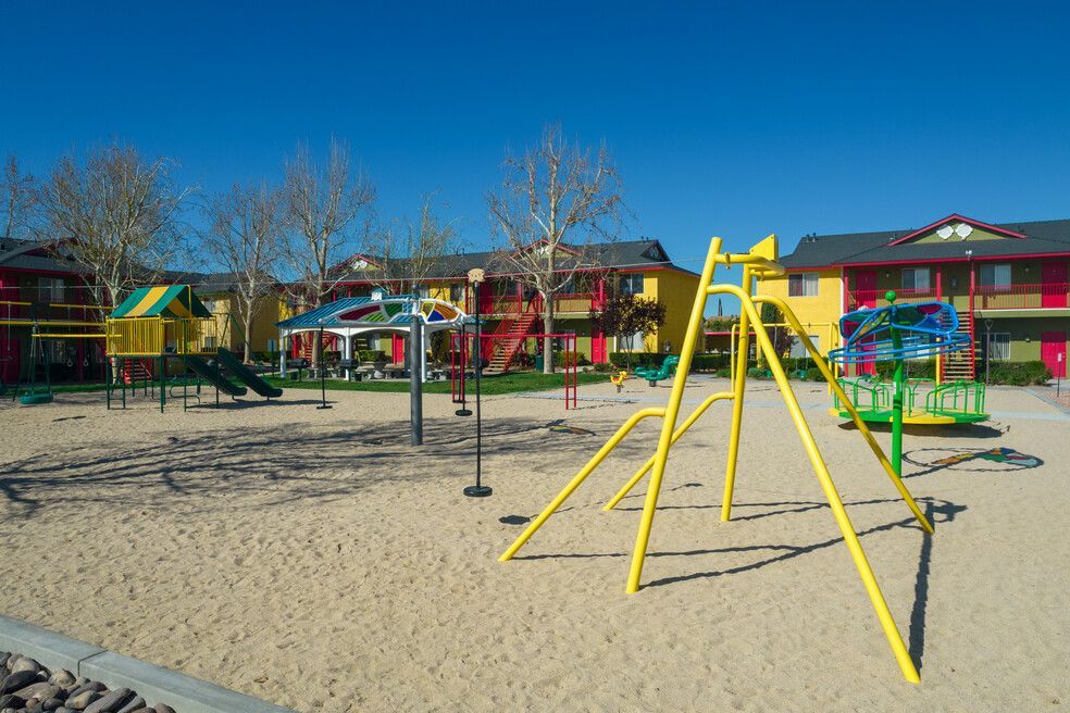 A playground with a yellow swing set in the middle of it