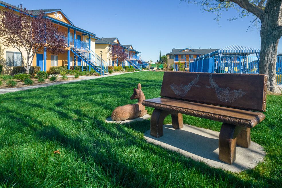A wooden bench with a statue of a deer on it in a park.