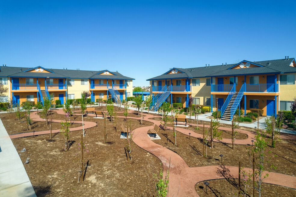 An aerial view of a row of apartment buildings surrounded by trees and paths.