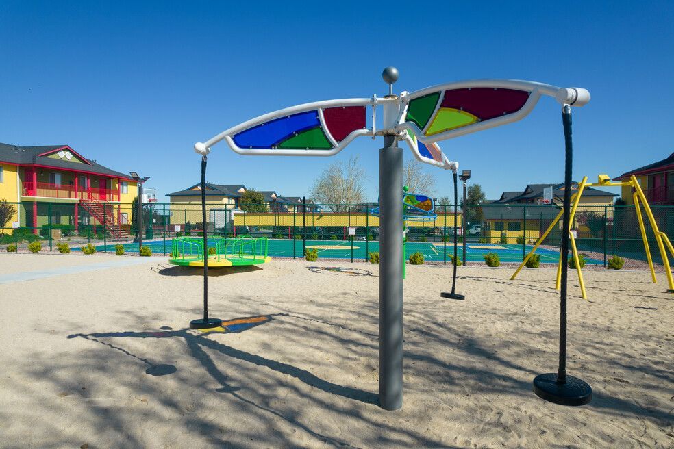 A playground with a colorful umbrella in the middle of it