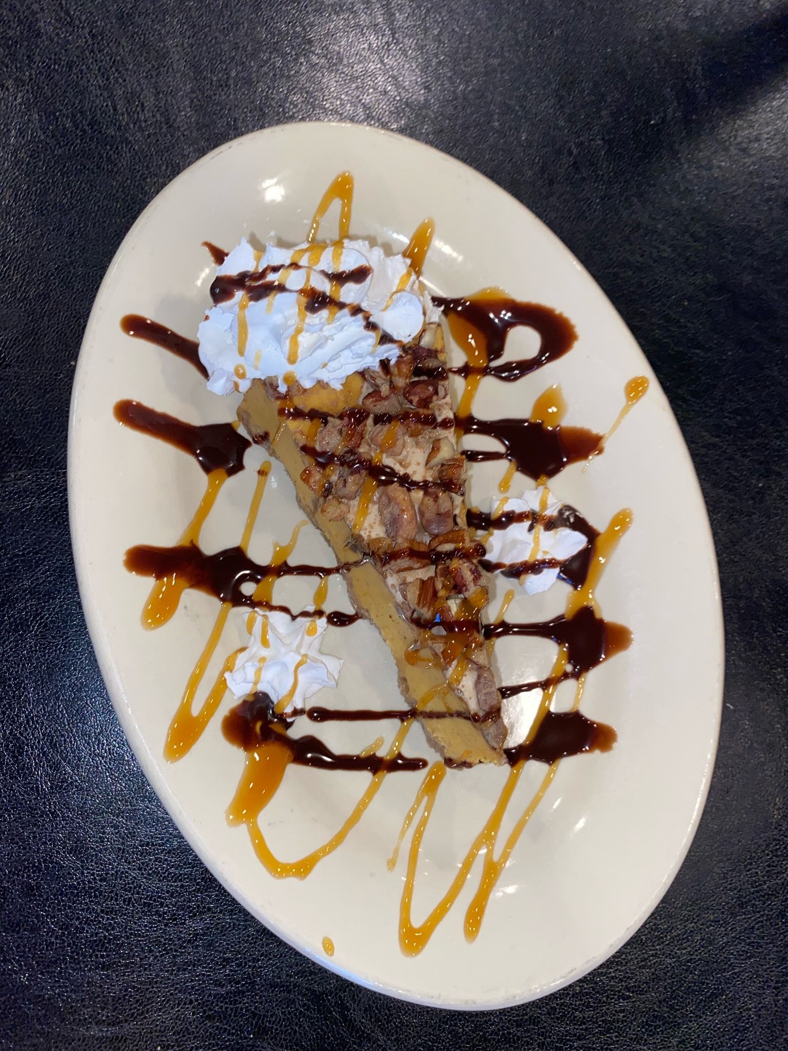 A white plate topped with rice and garlic bread. A white plate topped with a piece of pie with whipped cream and chocolate sauce.