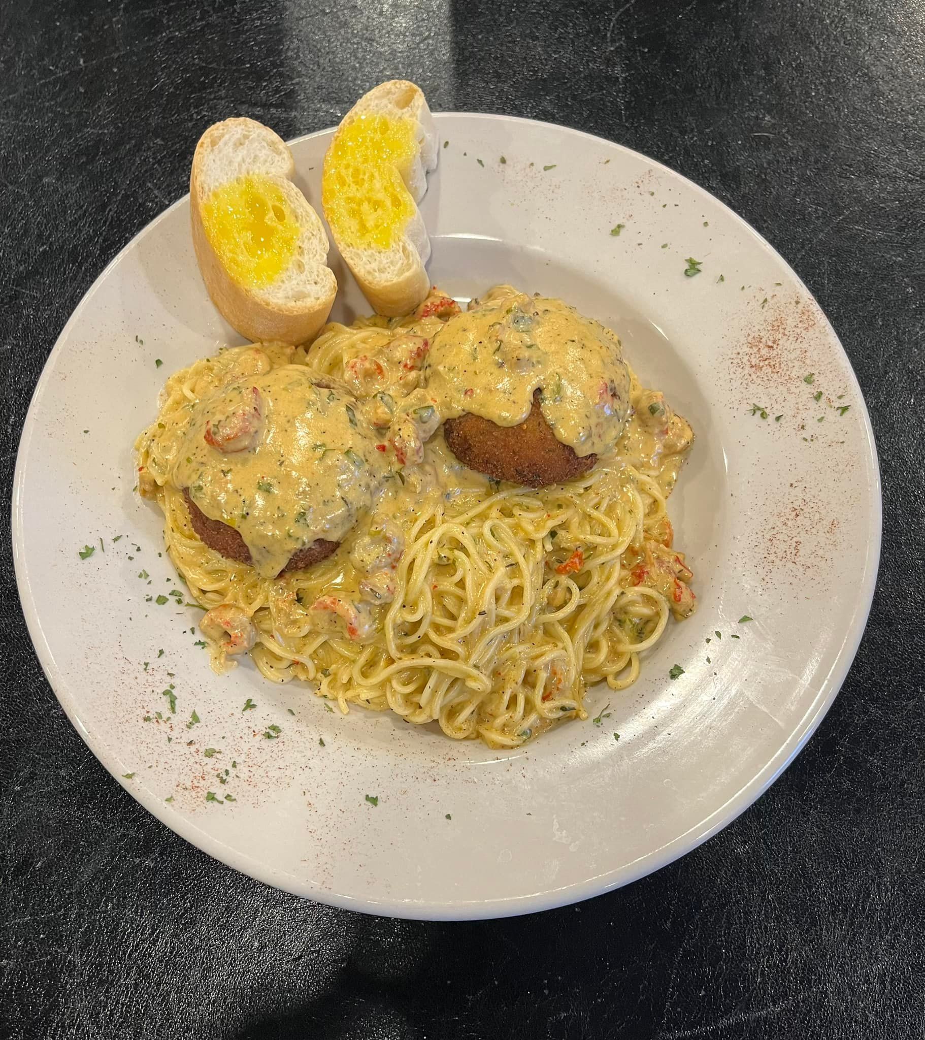 A white plate topped with spaghetti and garlic bread on a table.