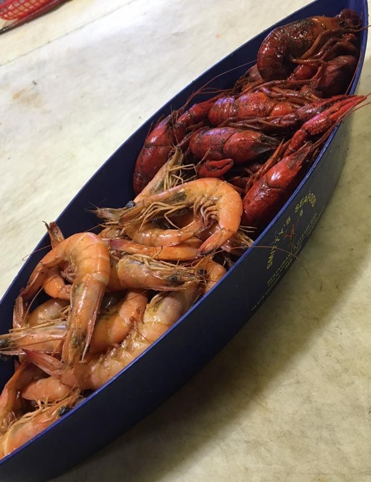 A blue boat filled with shrimp and crawfish on a table.