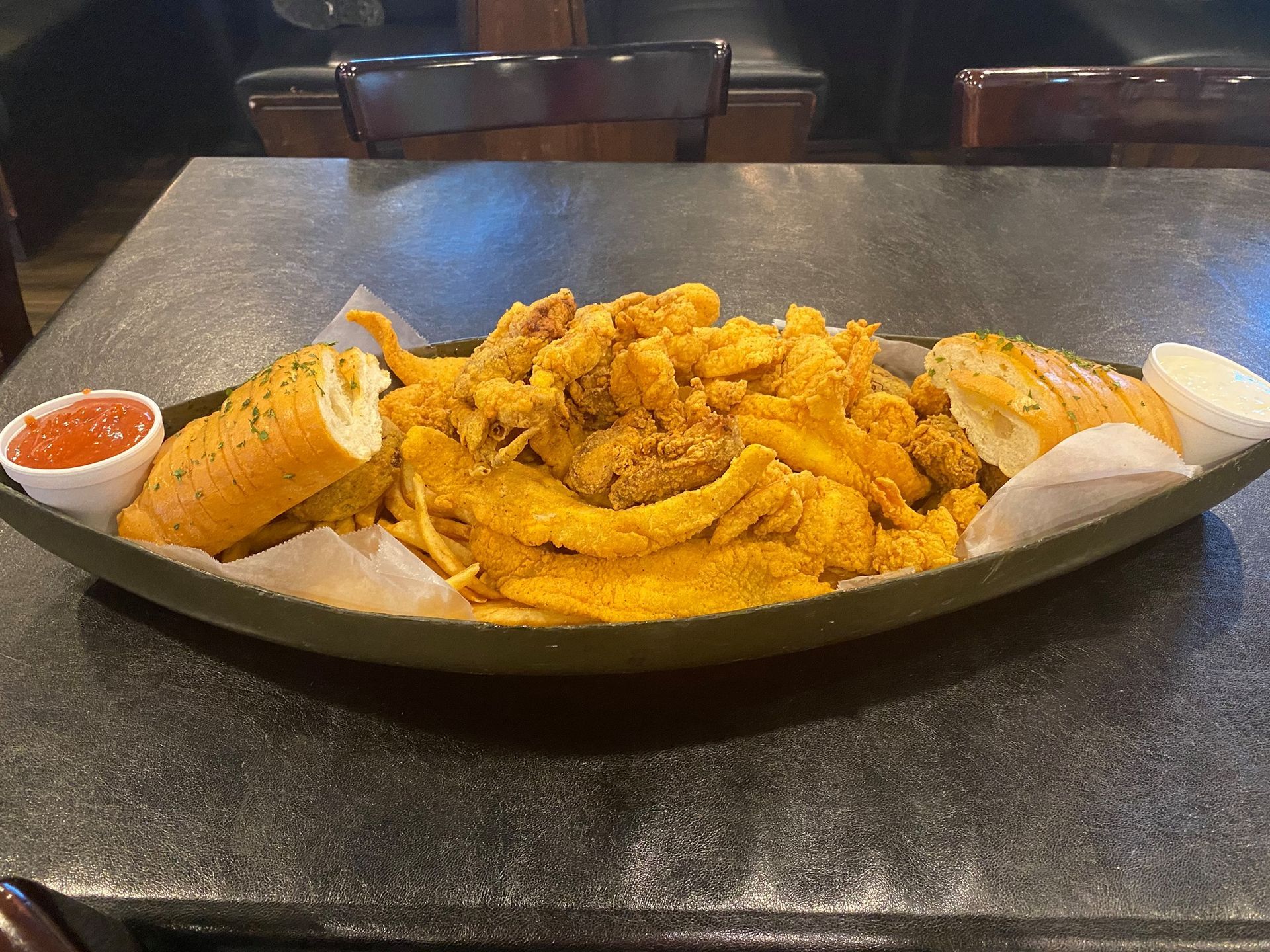 A plate of food with french fries and garlic bread on a table.