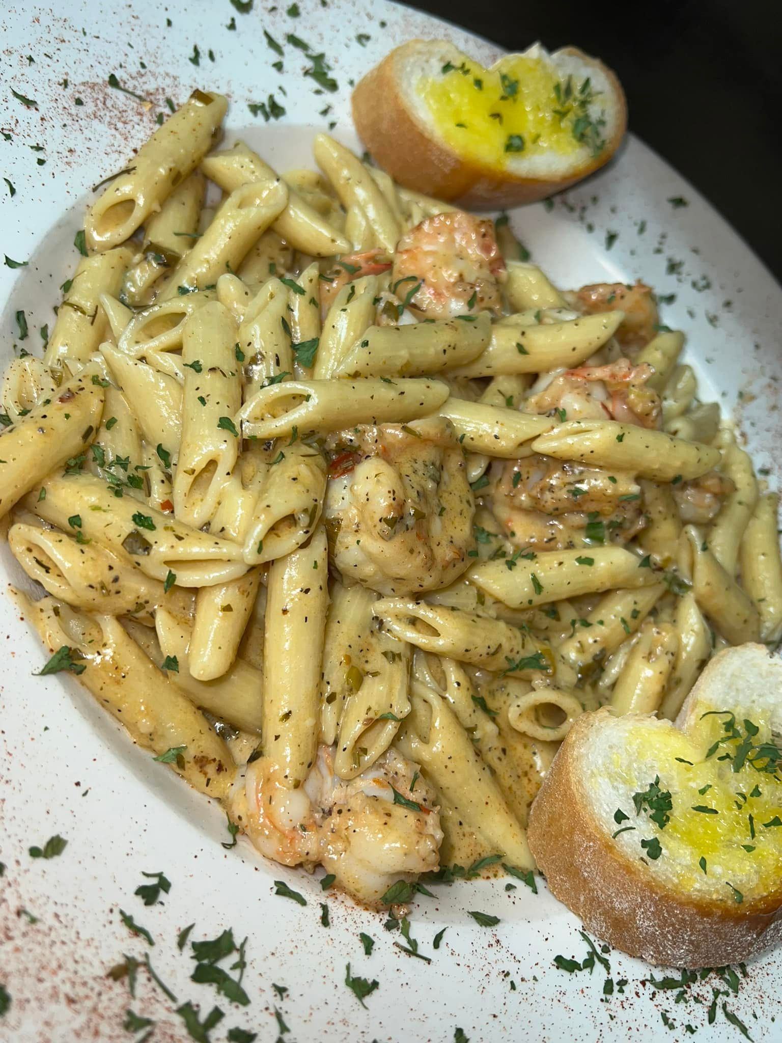 A plate of pasta with shrimp and garlic bread