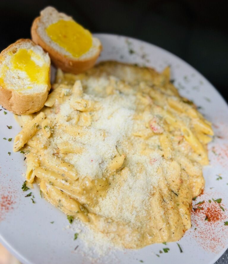 A white plate topped with spaghetti , shrimp , crab cakes and garlic bread.