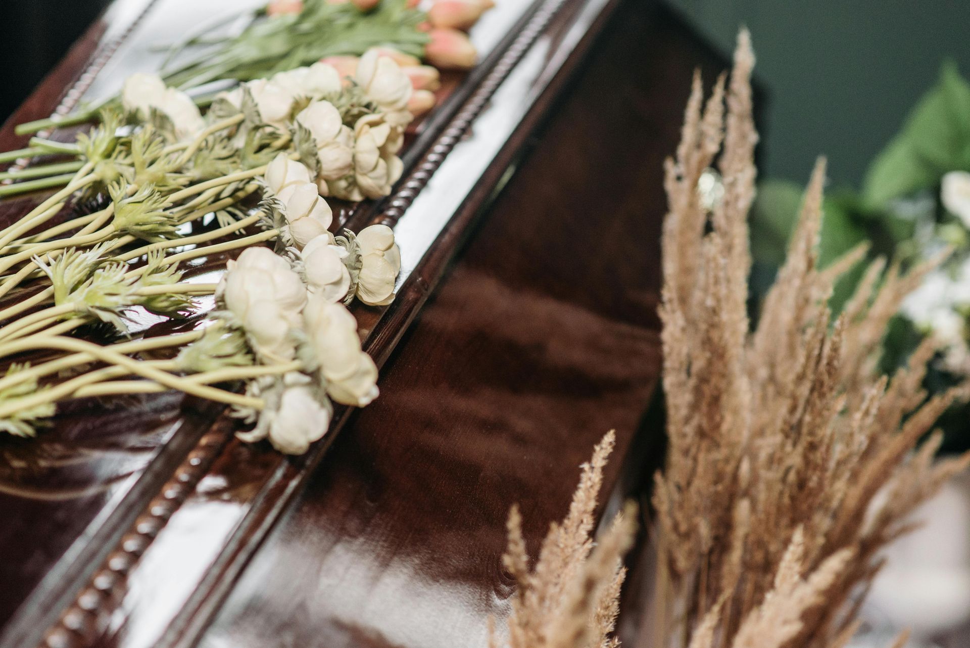 Dried floral arrangement with white berries and beige wheat in a dark wooden box