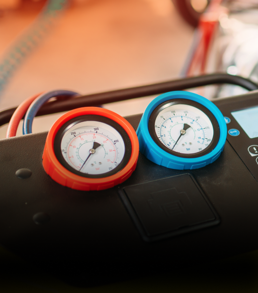 Two gauges, one red and one blue, on a black machine; hoses attached | NOR-CAL AUTOMOTIVE