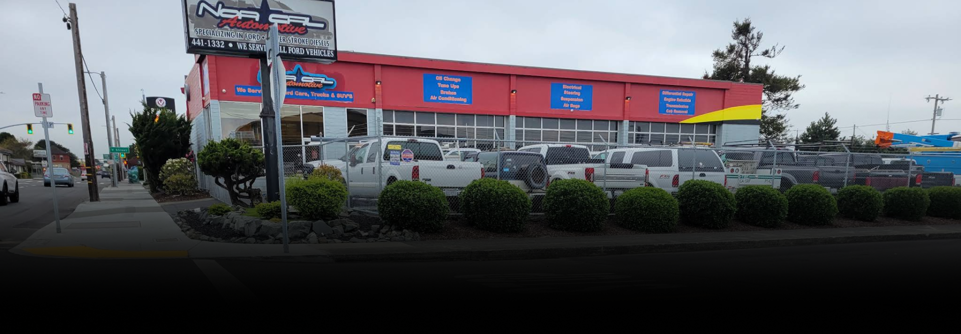 Car dealership building with red exterior and cars on display. Cloudy day | NOR-CAL AUTOMOTIVE