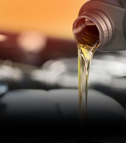 Motor oil pouring from a bottle into a car engine, golden liquid with a blurred background | NOR-CAL AUTOMOTIVE