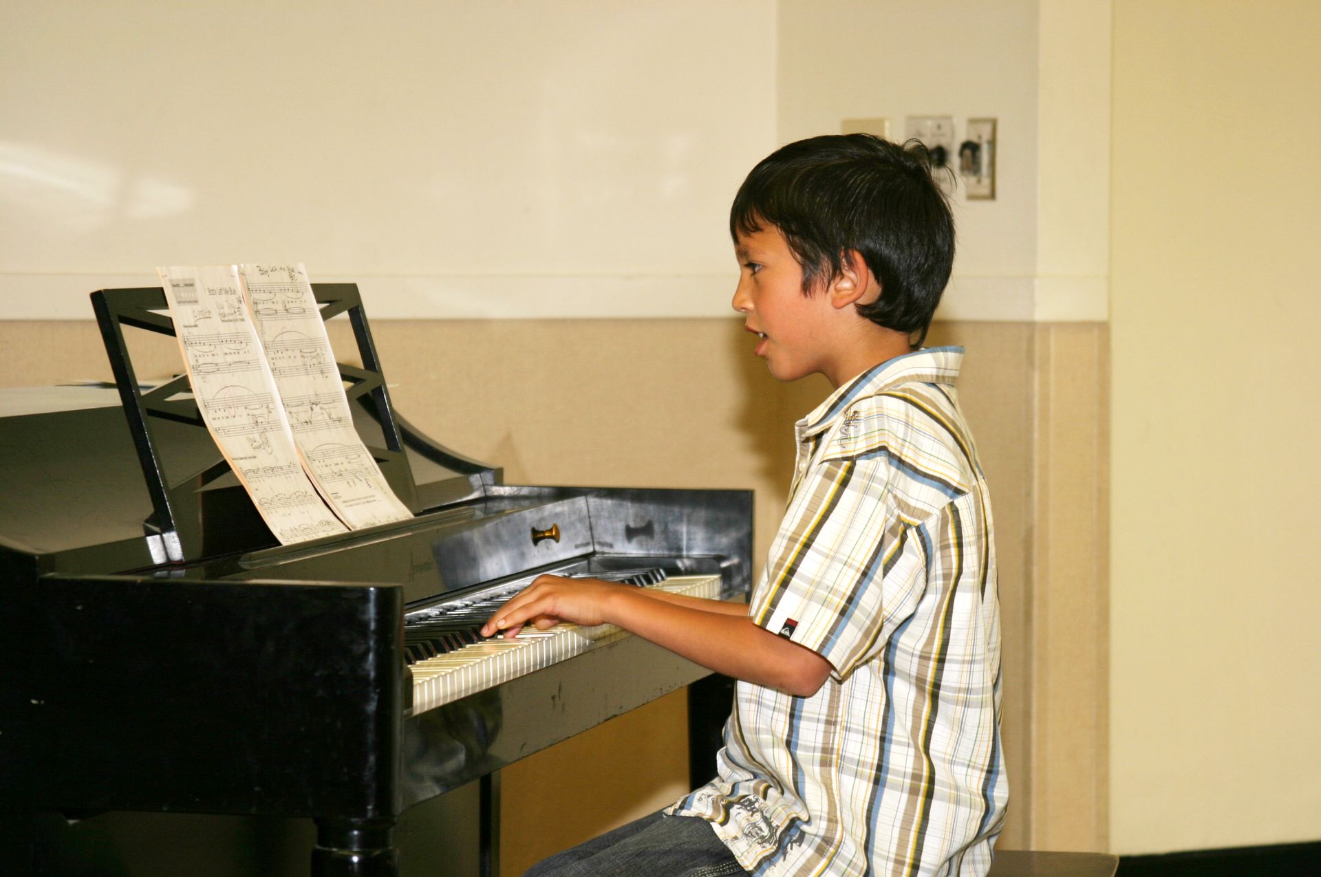 A young boy is playing a piano in a room.