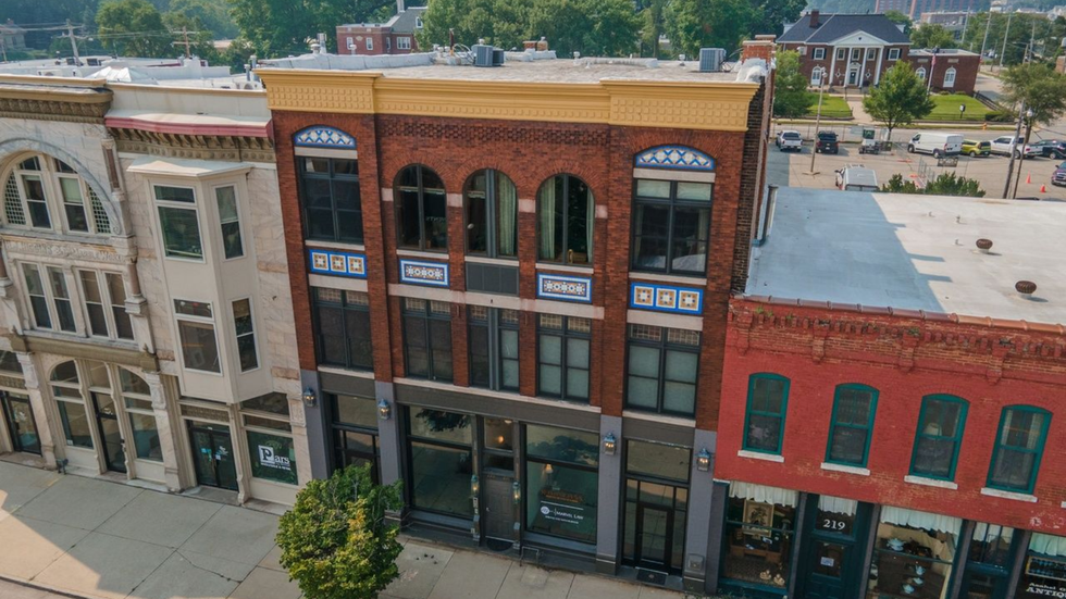 Aerial view of a row of historic storefront buildings with brick and stone facades along a downtown street.