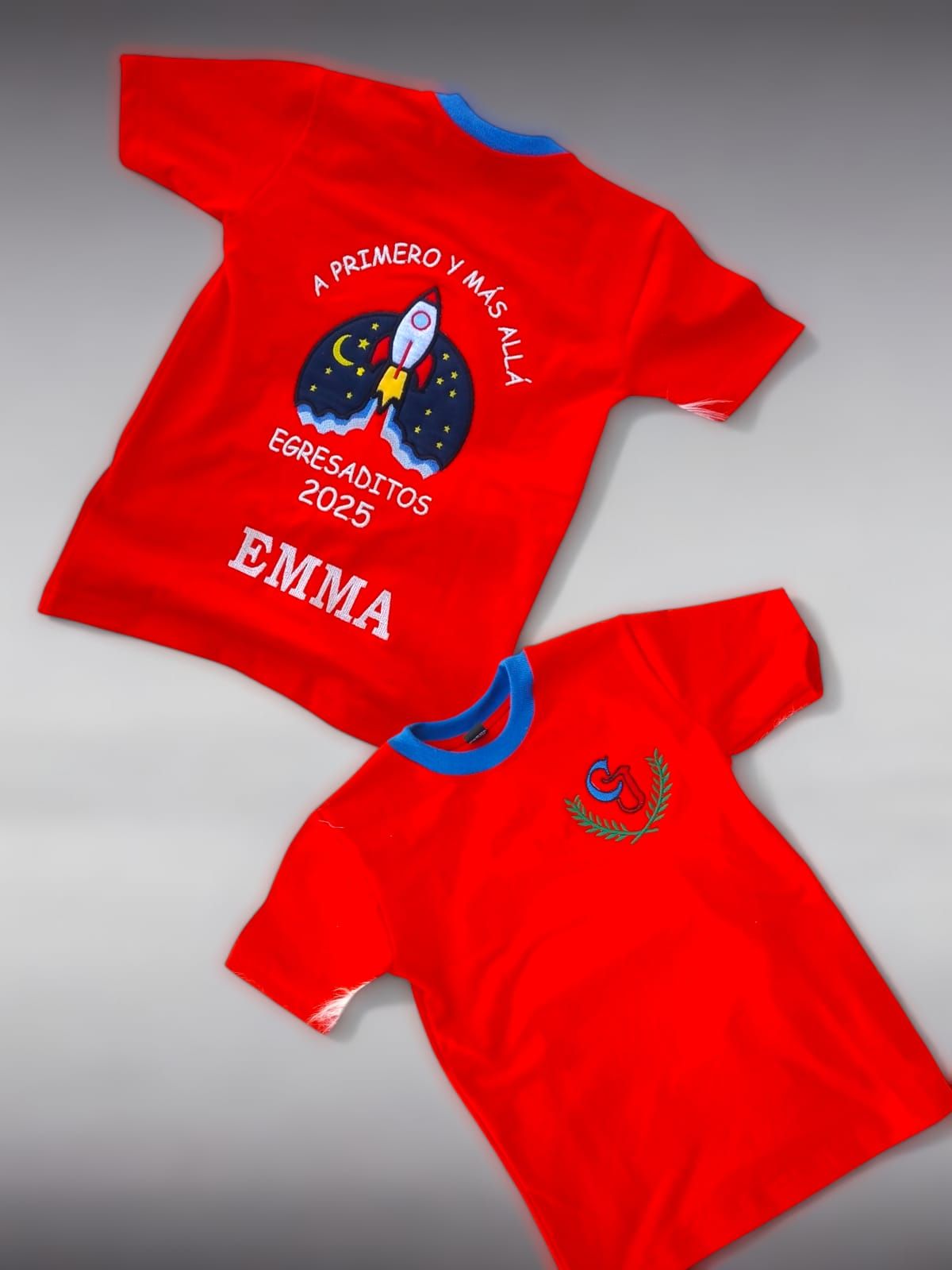 Dos camisetas rojas. La superior tiene un diseño de cohete y texto, y la inferior, un diseño en el pecho.