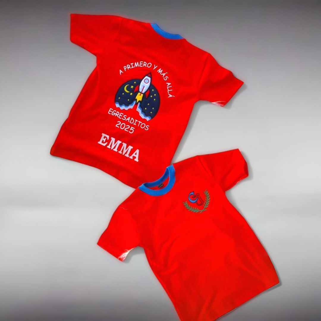 Dos camisetas rojas con ribete azul. Una tiene un diseño de cohete y la otra un pequeño emblema.