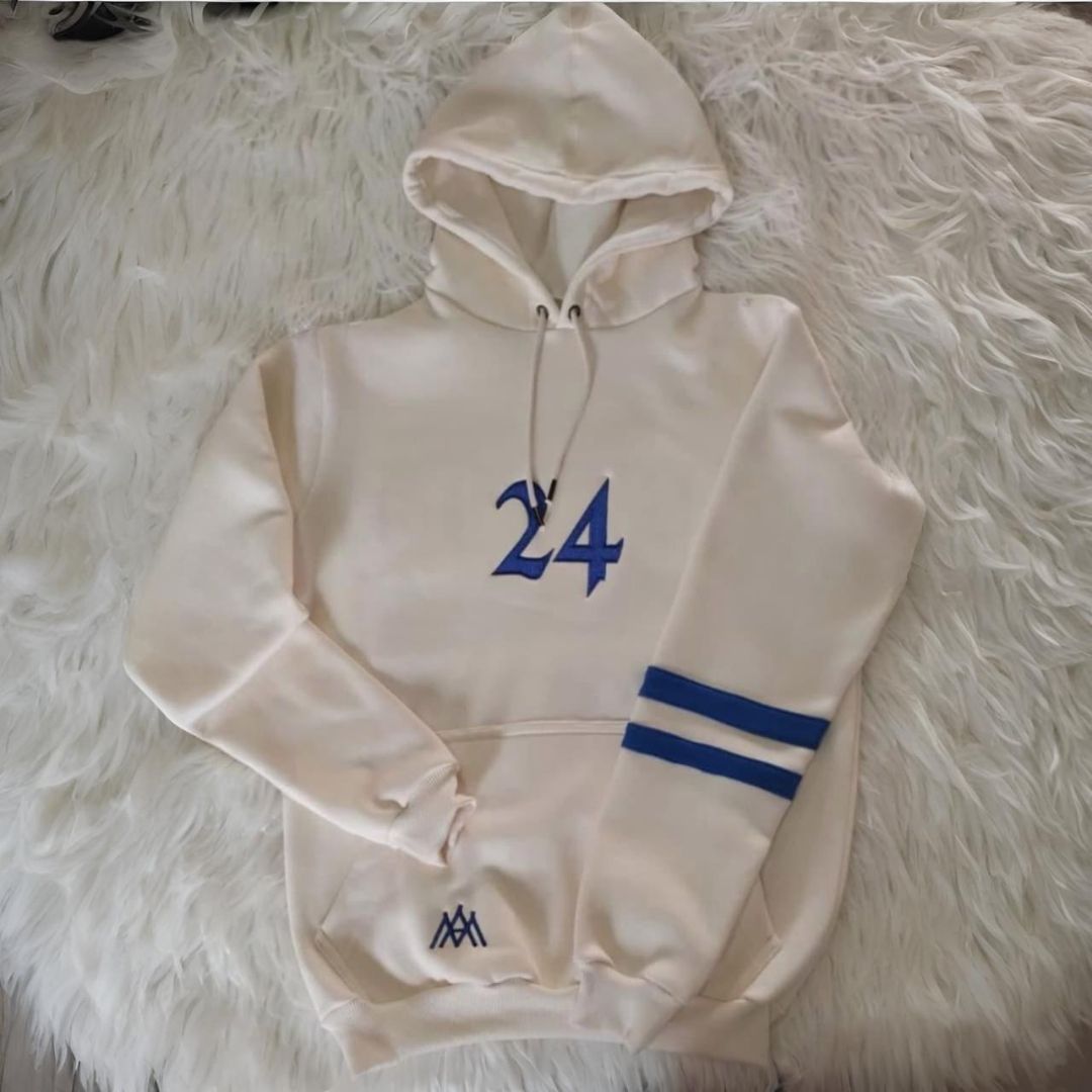 Sudadera con capucha de color crema con el número 24 en azul en la parte delantera y rayas azules en la manga.