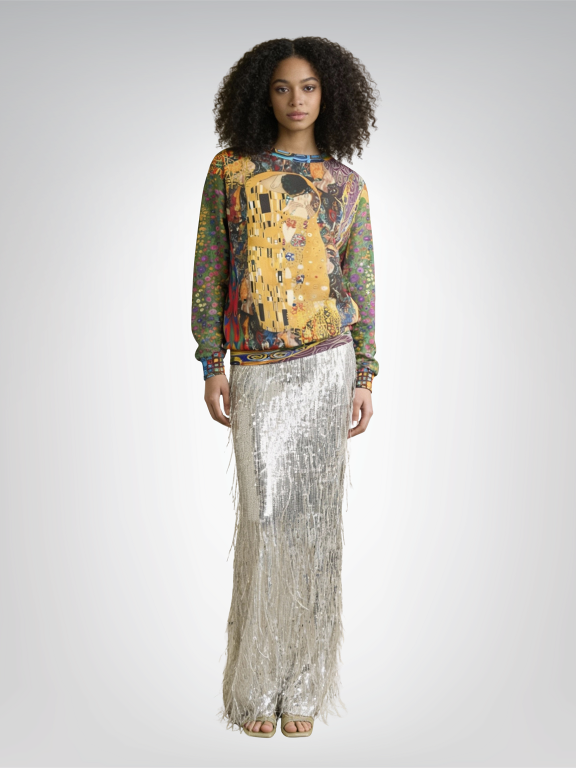 Woman in a sweater printed with a painting, and a long silver sequined skirt.