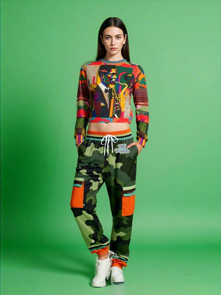 Woman in colorful top and camo pants, standing in front of a green backdrop.