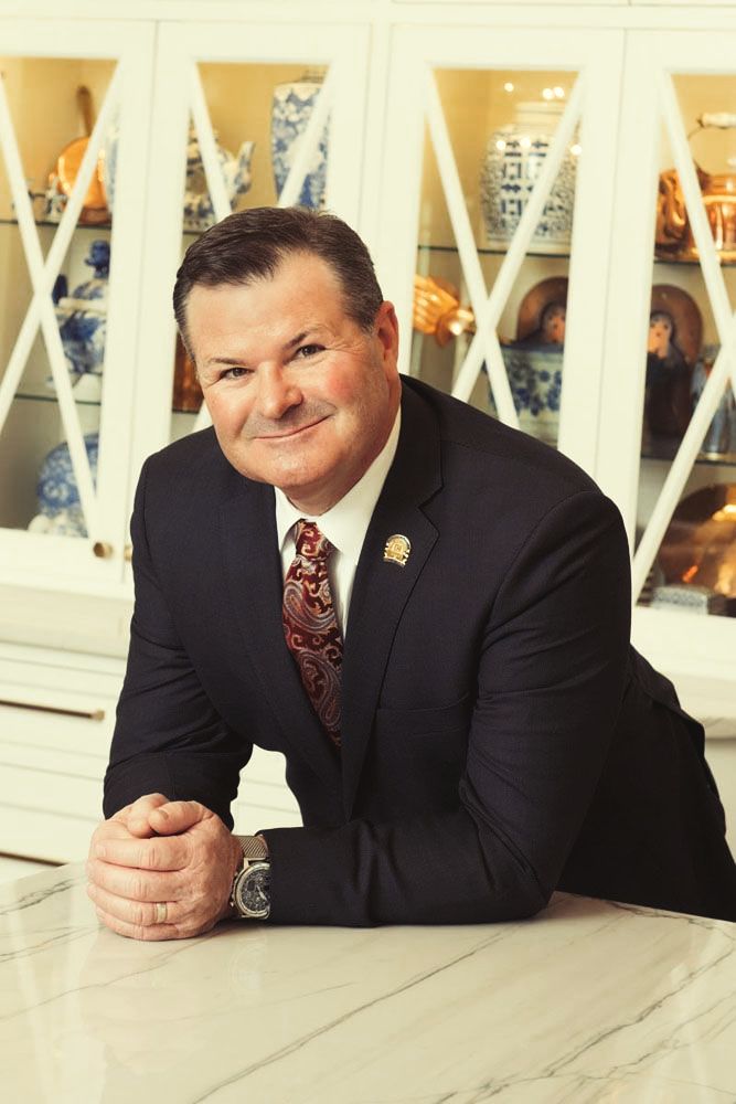 A man in a suit and tie is leaning on a counter.