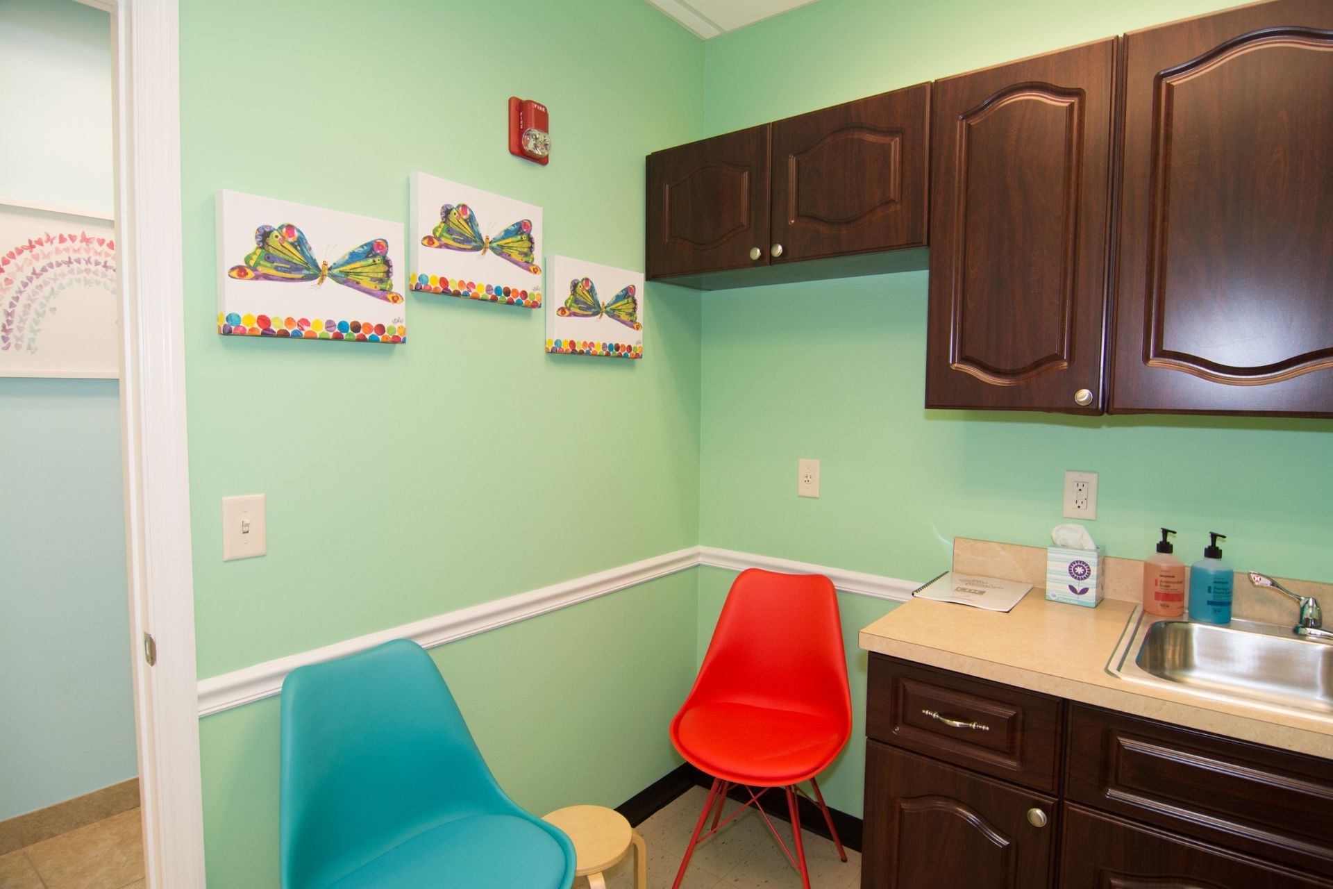 Photo inside the consultation room with blue and red chair beside the sink with brown countertop