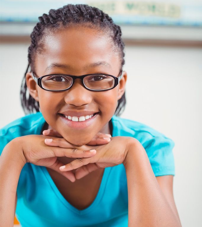 Black young girl smiling wearing a blue shirt and glasses